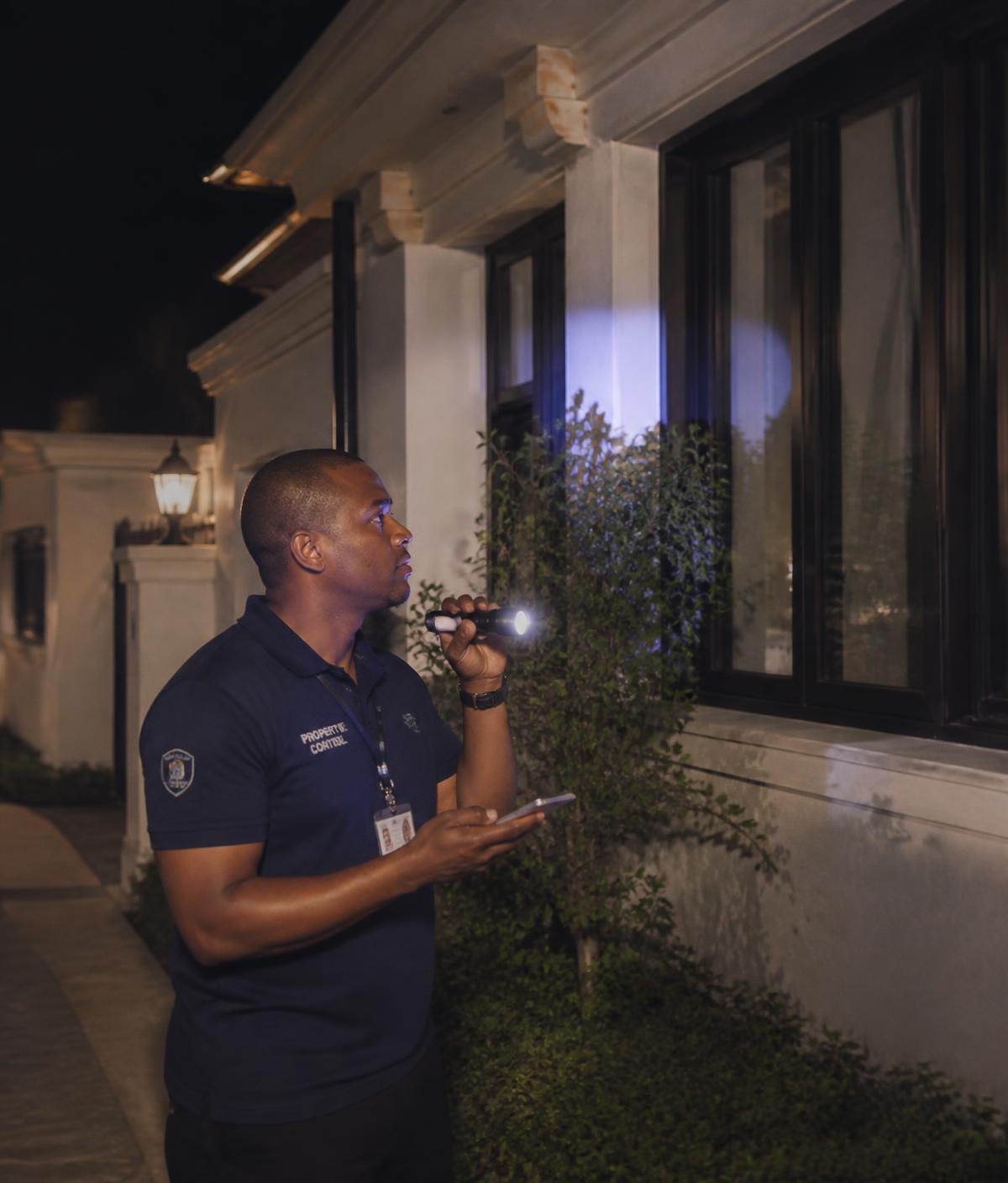 Técnico de Control In Time revisando de noche el perímetro y las ventanas de una vivienda